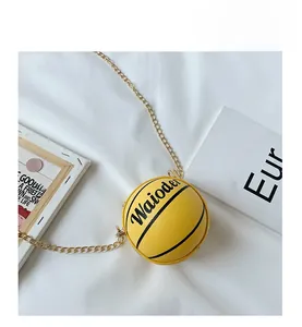 Detail of a bright yellow basketball-shaped crossbody bag with a gold chain strap