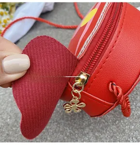 Detail of red heart-shaped kids bag with custom gold flower zipper and leather texture