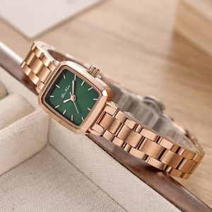 Vue macro d'une montre carrée à cadran vert émeraude et bracelet en métal doré rose