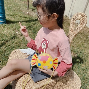 Cute candy-shaped yellow crossbody bag with colorful dots for kids on outdoor grass