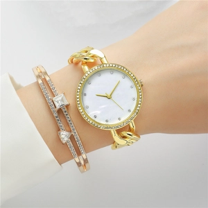 Gros plan d'une montre à quartz dorée avec lunette en strass et bracelet assorti
