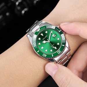Close-up of green dial quartz watch with silver steel strap and date display on wrist
