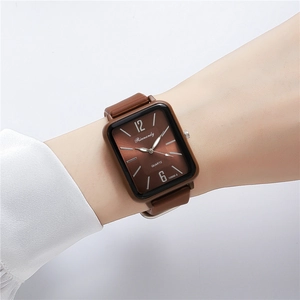 Close-up of a women's rectangular brown silicone watch with white numerals on the dial