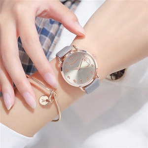 Detail of rose gold star and moon quartz watch with grey strap and matching bracelet