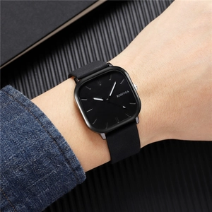 Gros plan d'une montre d'affaires carrée noire minimaliste avec bracelet en cuir au poignet