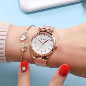 Gros plan d'un ensemble montre en maille or rose et bracelet feuille pour femme