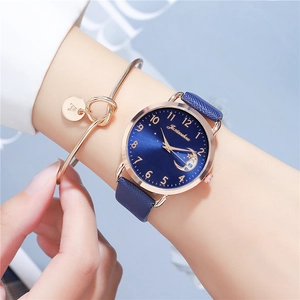 Detail of blue leather strap watch and gold letter A bracelet on model wrist
