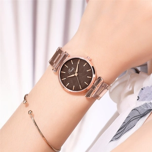 Close-up of elegant rose gold mesh watch with a chocolate brown dial on female wrist