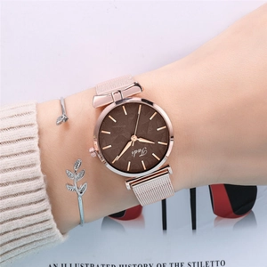Ensemble montre en maille or rose et bracelet feuille d'argent porté au poignet