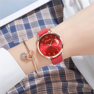 Close-up of a red star and moon dial watch with matching gold bracelet on a wrist
