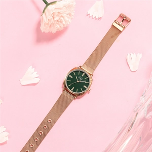 Detail of rose gold mesh strap watch with emerald green dial and crystal markers