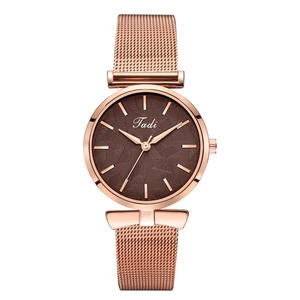 Gros plan d'une montre en maille or rose avec cadran marron et détails de motif de feuille