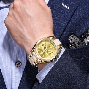 Detail of Geneva gold steel watch on wrist paired with a navy business suit