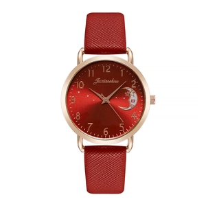 Detailed view of red leather strap and rose gold star and moon dial on lady's watch