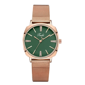 Detailed view of women's rose gold mesh watch with diamond accents on a green dial