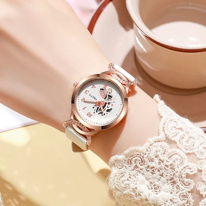 Dettaglio dell'orologio in oro rosa con cinturino in pelle bianca sul polso di una donna