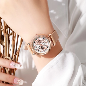 Gros plan d'une montre squelette avec boîtier or rose et bracelet en cuir brun au poignet