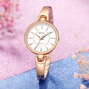 Gros plan d'une montre à quartz minimaliste or rose avec bracelet fin sur fond décoratif
