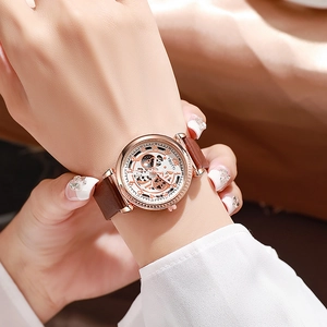 Gros plan d'une montre squelette en or rose de luxe avec bracelet en cuir marron et cristaux