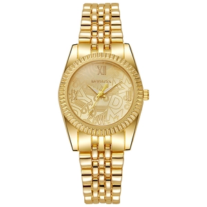 Détail d'une montre à quartz dorée avec lunette cannelée et cadran à motifs