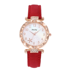 Detail of rose gold quartz watch with rhinestone bezel and dark red suede strap