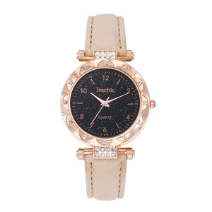 Détail du cadran noir étoilé et de la lunette en strass dorée sur une montre à quartz beige
