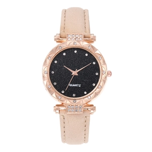 Close-up of rose gold starry dial watch with rhinestone markers and beige leather strap