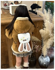 Close-up of plush rabbit ear detail and vintage plaid lining on a cute kids backpack