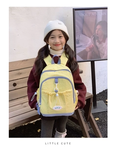Girl wearing yellow and purple waterproof nylon school backpack in an outdoor scene