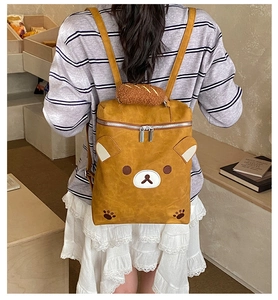 Detail of cute yellow cartoon bear backpack with plush bread handle and character pattern