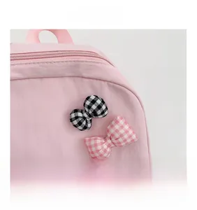 Detail view of pink nylon school backpack with cute plaid bow ties and zipper