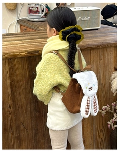 Rear view of a child wearing a brown corduroy backpack with cute plush rabbit ears