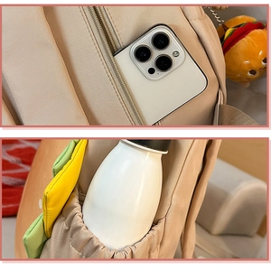 Detail of beige backpack featuring side water bottle pocket and burger charm attachment