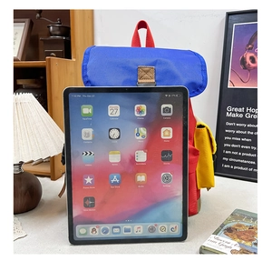 Detail of color-block kids backpack showing blue flap and red body with leather buckles