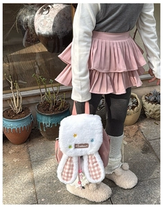 Close-up of plush bunny ears with pink plaid texture and beaded drawstring on child backpack