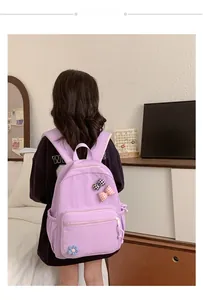 Detail of lavender school bag with checkered bows and flower pins on a child model