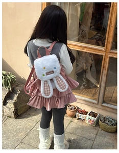 Detail of plush rabbit ear backpack with pink plaid lining and floral accents on straps