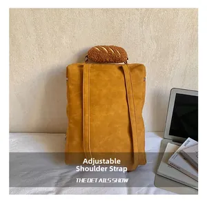 Detail showing mustard yellow backpack back with adjustable straps and bread plush handle