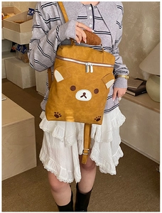 Cute yellow cartoon bear backpack shown in lifestyle setting with plush handle detail