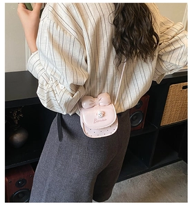 Mini sac bandoulière rose avec grand nœud et breloque chien porté par un mannequin