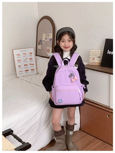 Detail of light purple schoolbag with cute bow patches worn by a child in a bedroom