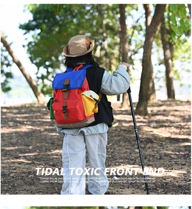 Close-up of a colorful kids outdoor backpack with red, blue, and yellow panels in nature