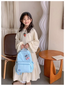 Sky blue kids backpack featuring cute floral and bow details held by a little girl