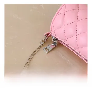 Close-up of pink quilted stitching detail with silver metal zipper and chain strap