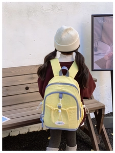 Detail view of yellow school backpack with blue contrast straps and white drawstrings