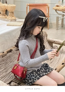 Close-up of red quilted mini bag for kids with gold twist lock and chain strap