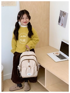 Detail view of beige kids backpack showing durable fabric and drawstring pocket