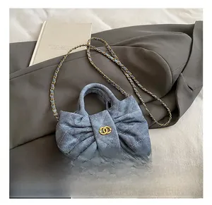 Close-up of quilted denim bow handbag with gold chain strap on a blazer background