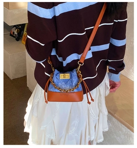Détail du sac à bandoulière en denim bicolore avec fermoir rotatif doré et chaîne