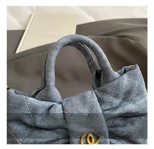 Detail of blue denim crossbody bag with quilted pattern and gold logo fastener